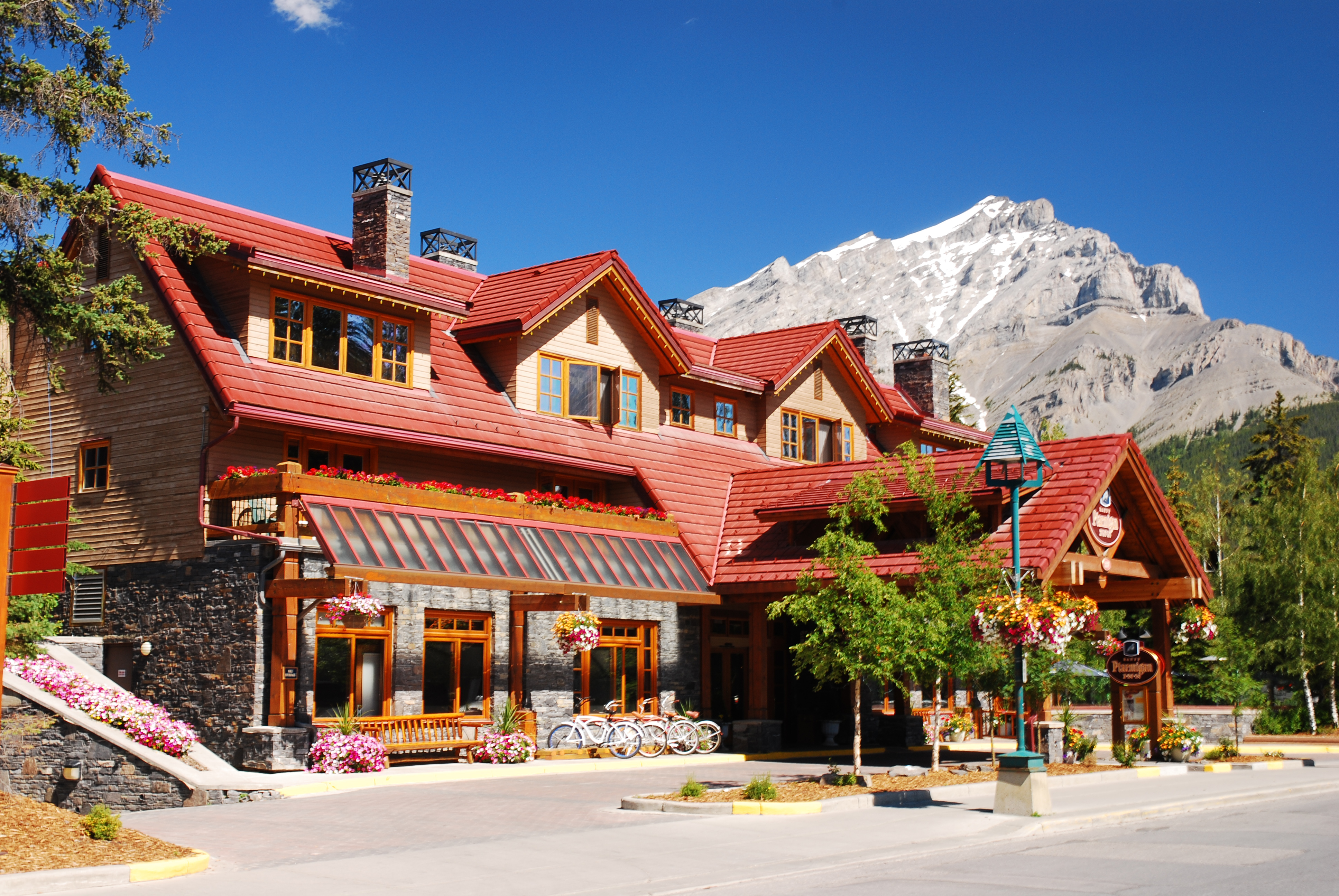 Exterior of Banff Ptarmigan Inn in the summer with mountains behind