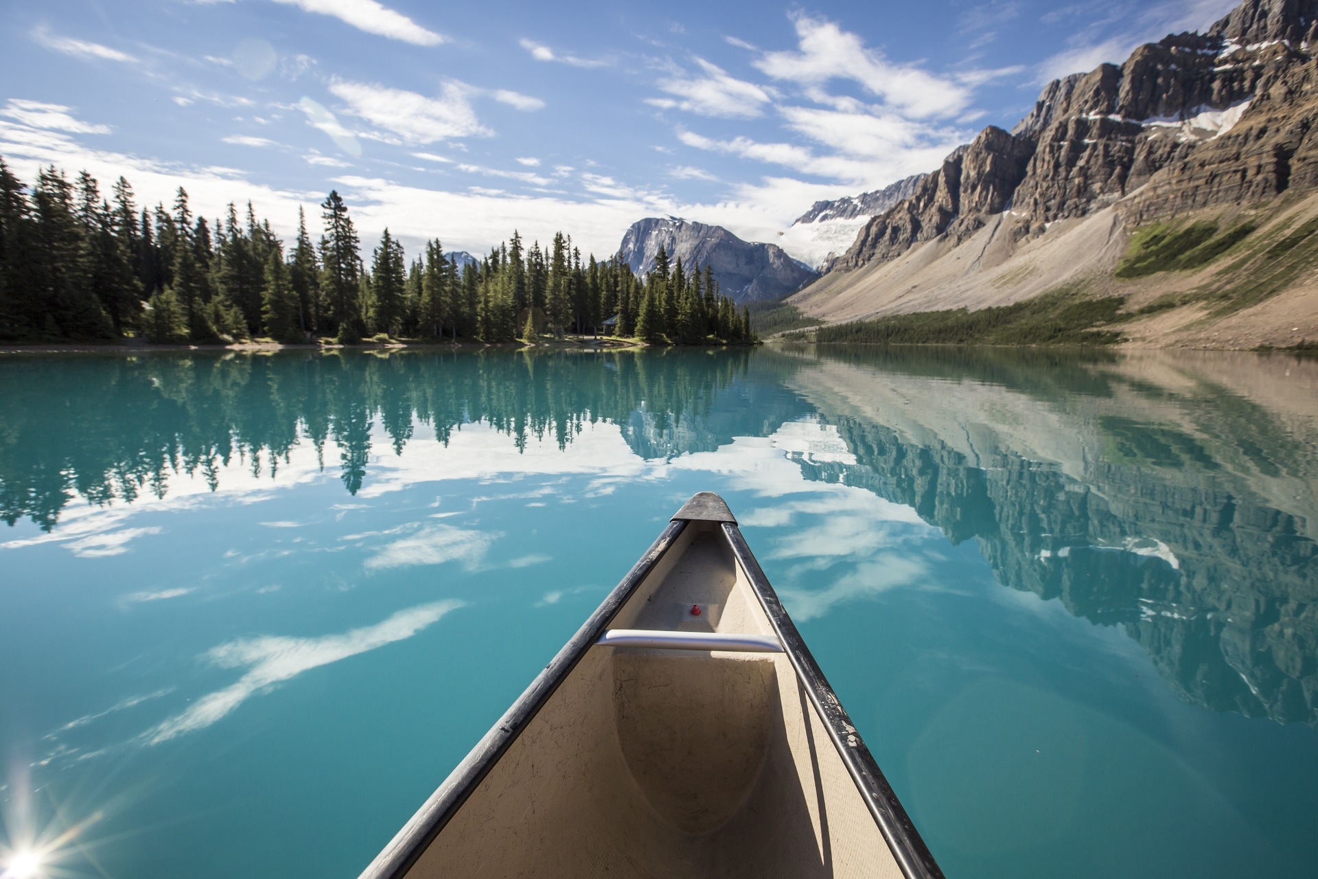 Tip of a canoe on a turquoise lake with mountains in the background
