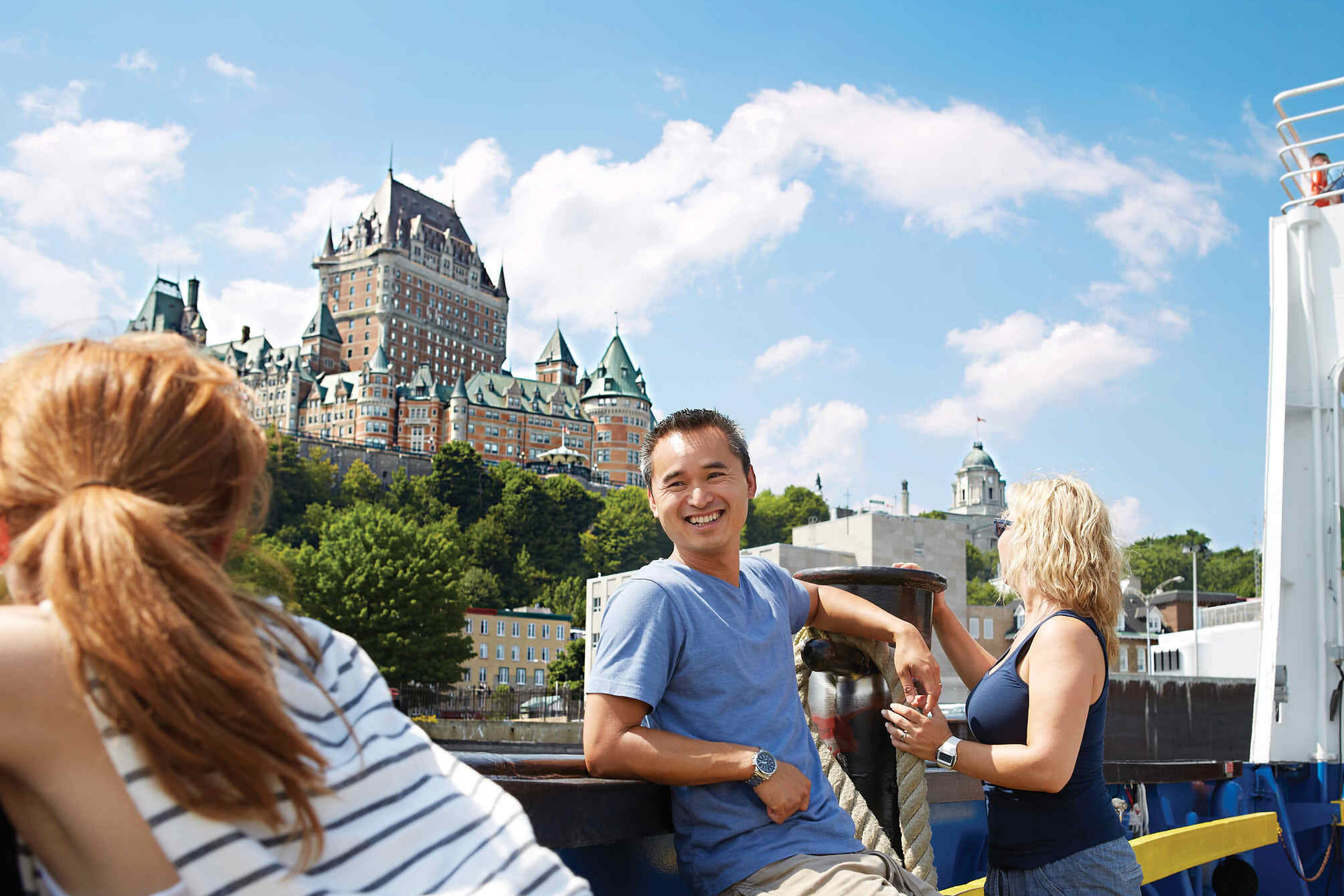 A young man leans against the side of a ferry as it cruises past the Fairmont Chateau Frontenac in Quebec City.