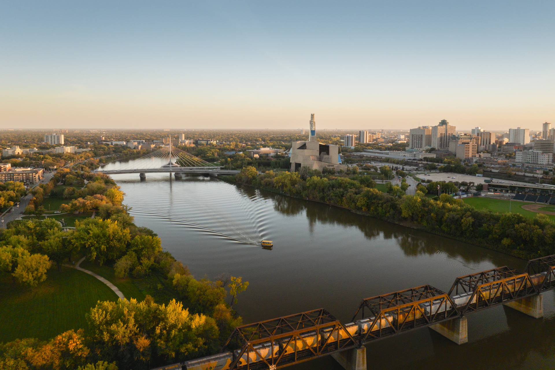 A small boat travels along the river in Winnipeg, Manitoba at sunset