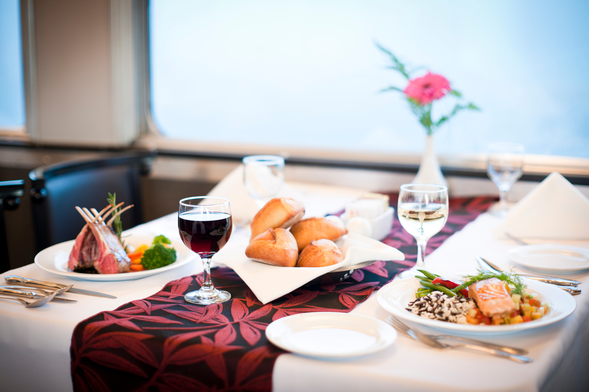 A table set with a fine dining meal with wine in a train dining car
