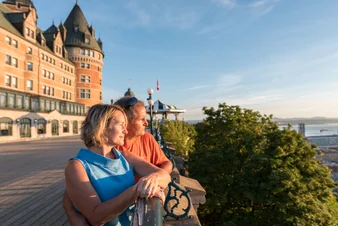 A mature couple admires the view over Dufferin Terrace in Quebec City with the Fairmont Chateau Frontenac in behind