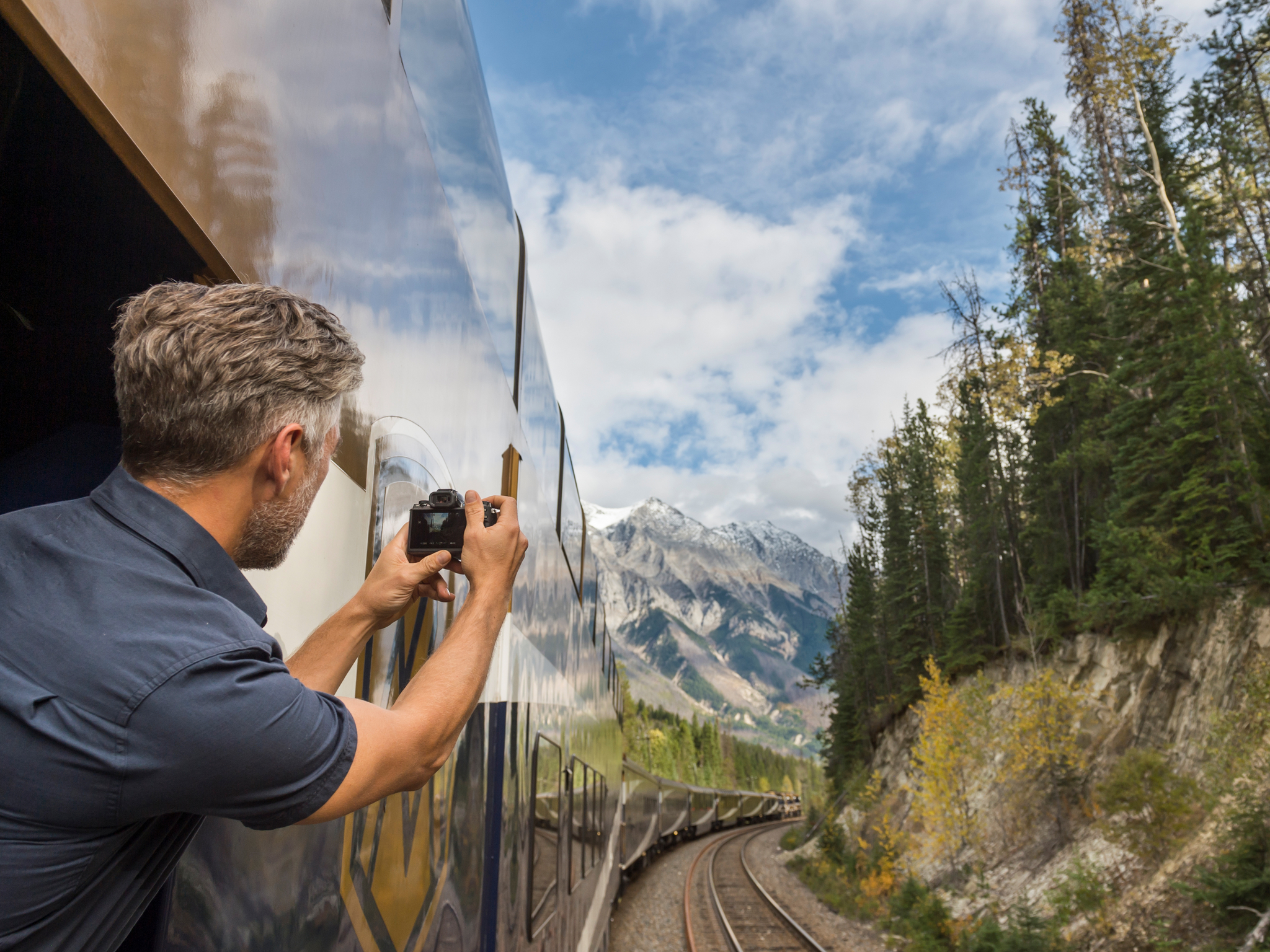 A guest takes photos from the outdoor viewing platform in the Goldleaf coach