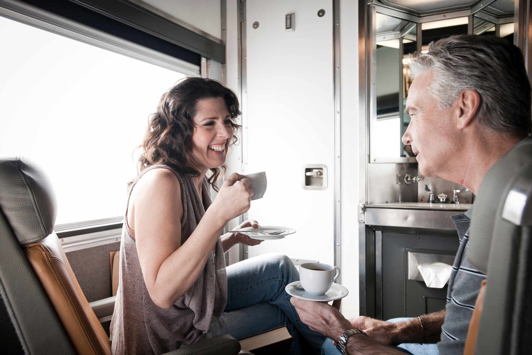 Man and woman enjoy a cup of coffee in VIA Sleeper Plus on the Vancouver to Toronto train