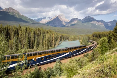 Rocky Mountaineer train going through Banff National park with mountains