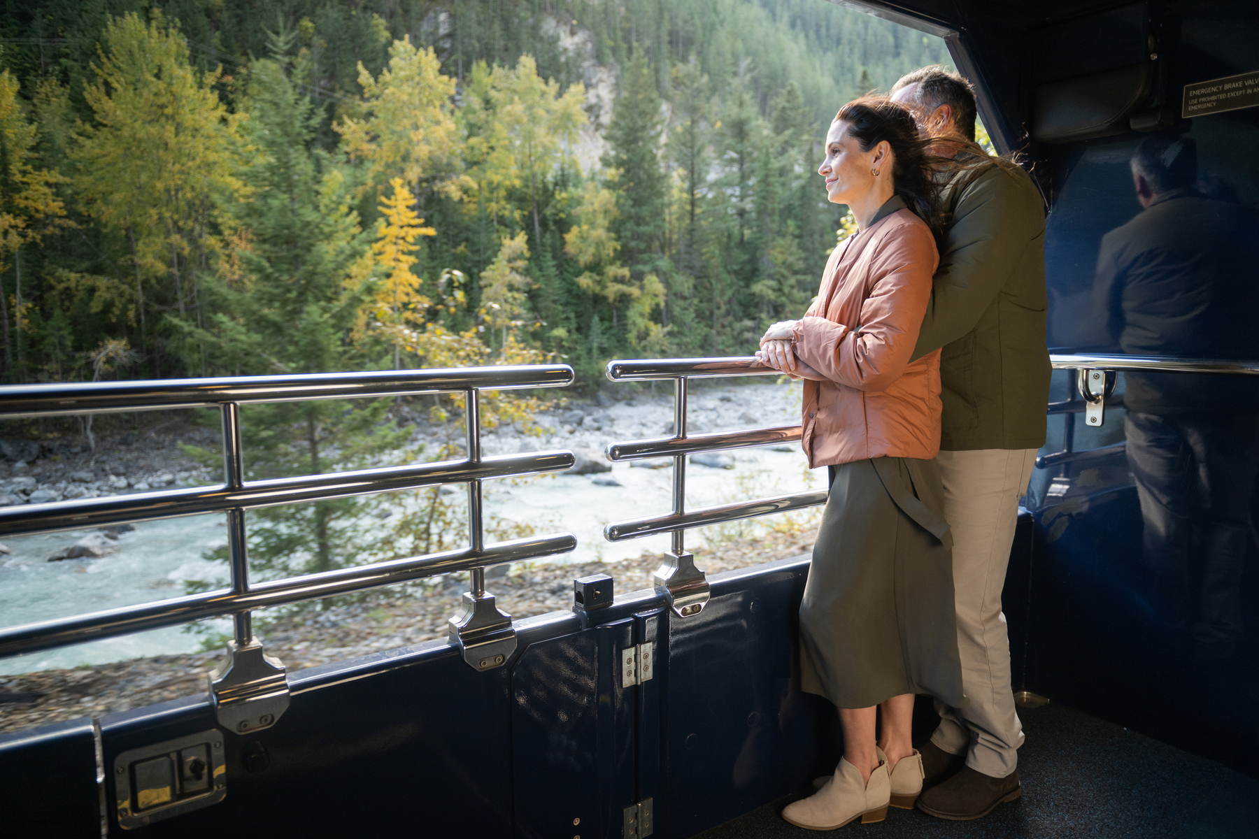 Couple standing on the GoldLeaf outdoor viewing platform on the luxury Rocky Mountaineer train