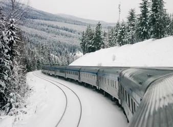 VIA Rail train, The Canadian, en route during winter as trees and mountains are powdered with white snow