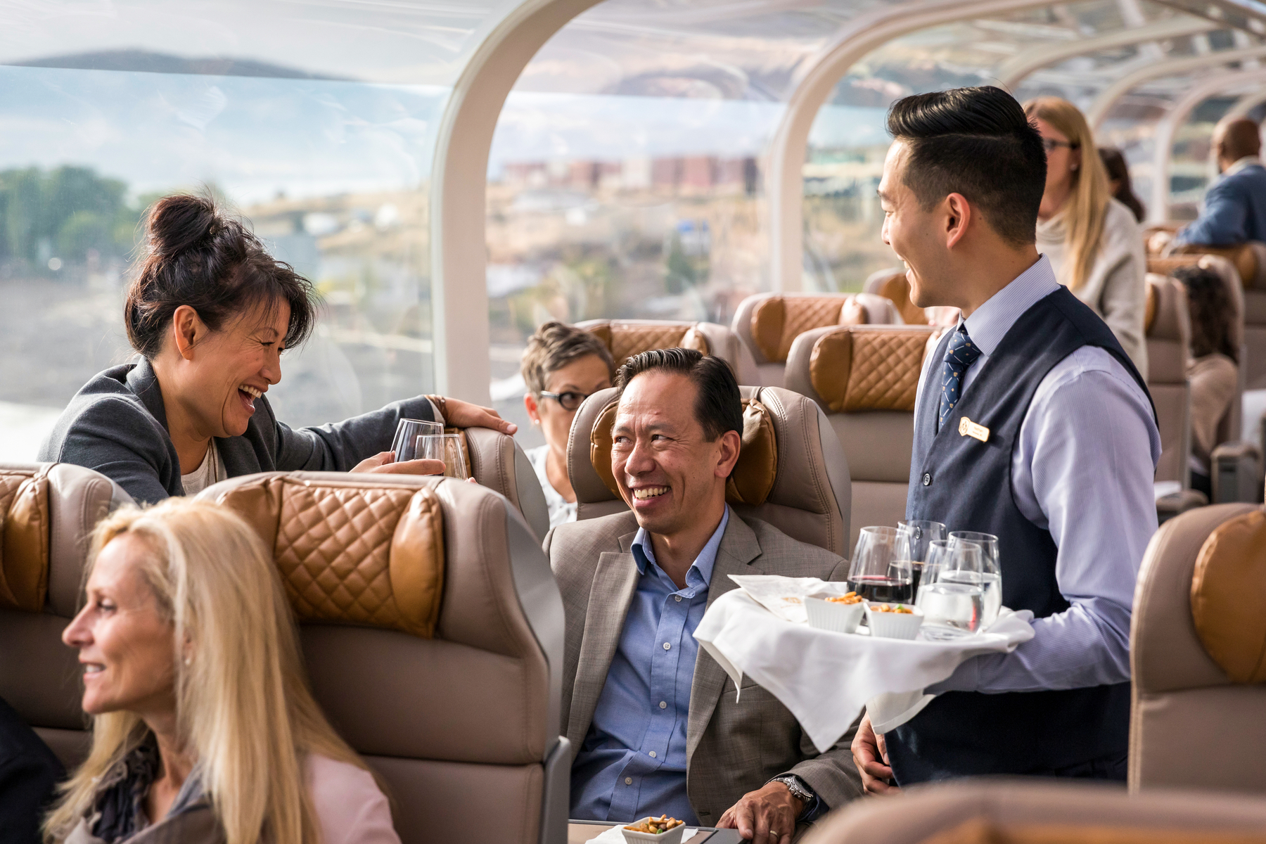 Onboard host serves wine to couple in the GoldLeaf dome