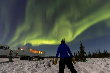 Onlooker standing near Tundra Buggy watches Northern Lights in Churchill, Manitoba