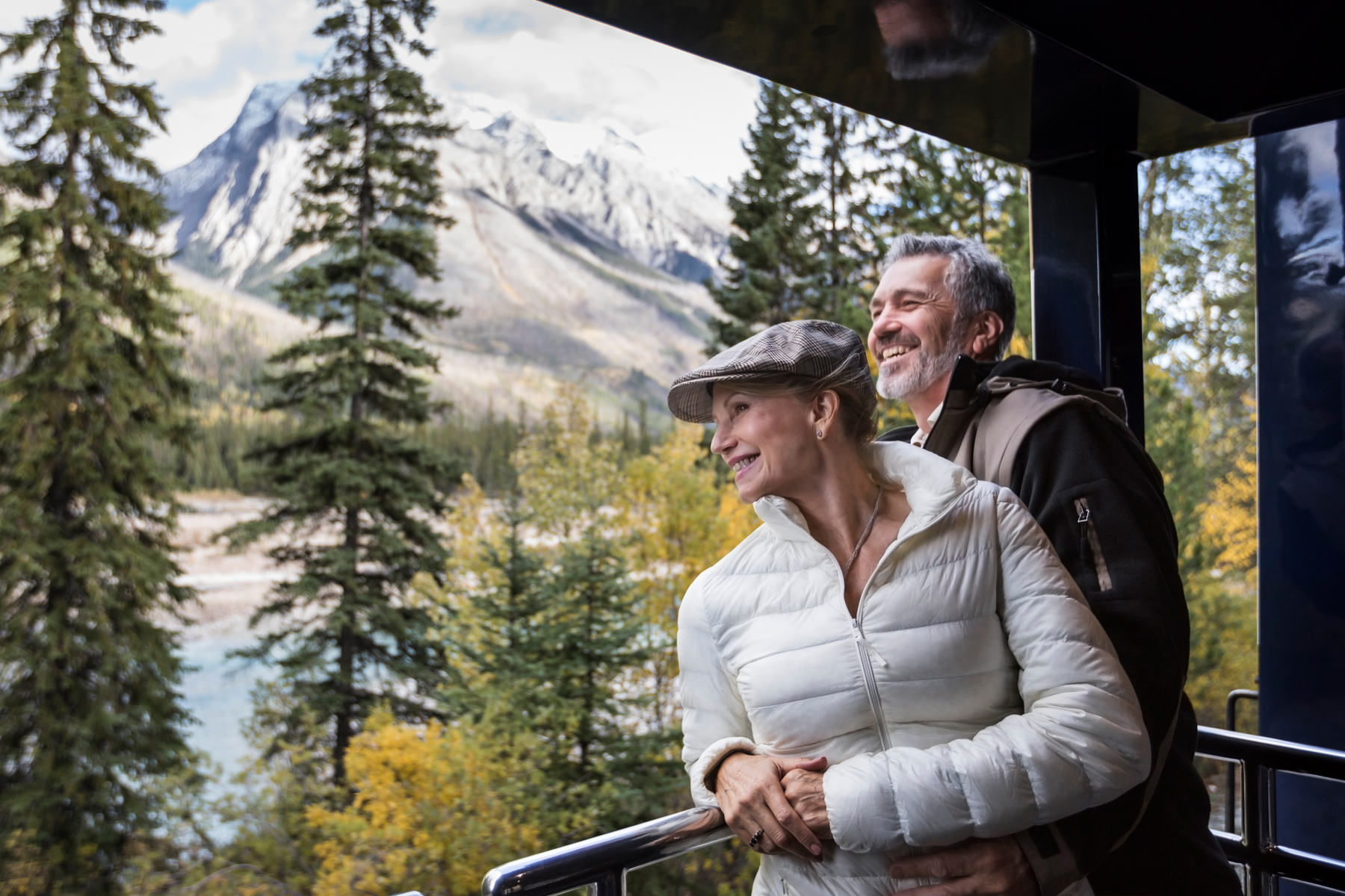 Couple enjoys the fall views from the outdoor viewing platform on the Rocky Mountaineer train from Vancouver to Banff