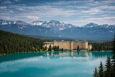 View of Fairmont Chateau Lake Louise with turquoise water and mountains in behind