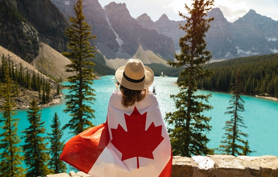 Woman with Canada flag wrapped around her overlooking Moraine Lake
