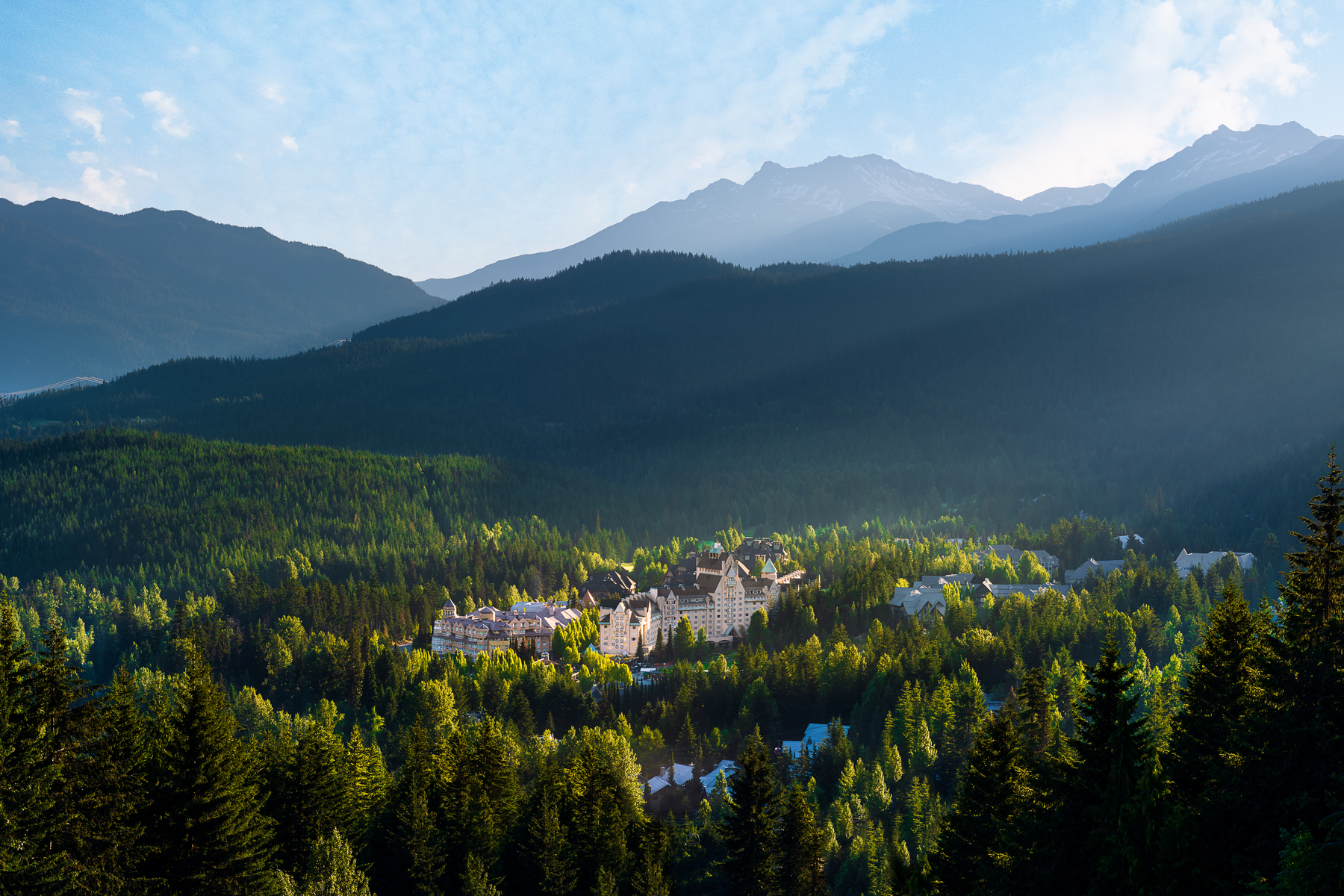Aerial view of Whistler with Fairmont Chateau Whistler hotel in the centre, surrounded by trees and mountains in summer