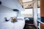 VIA Rail Sleeper cabin for two with bunks beds beside a window, a laptop on the lower bunk, and a vanity mirror and door.