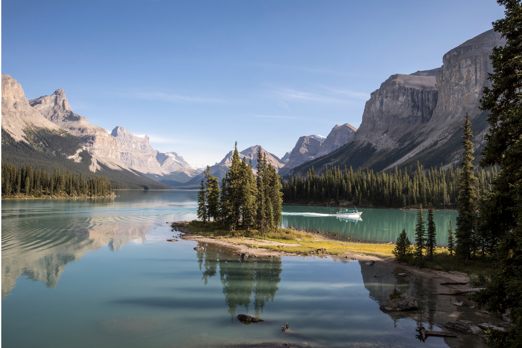 A small boat drives behind Spirit Island on Maligne Lake in the Rockies