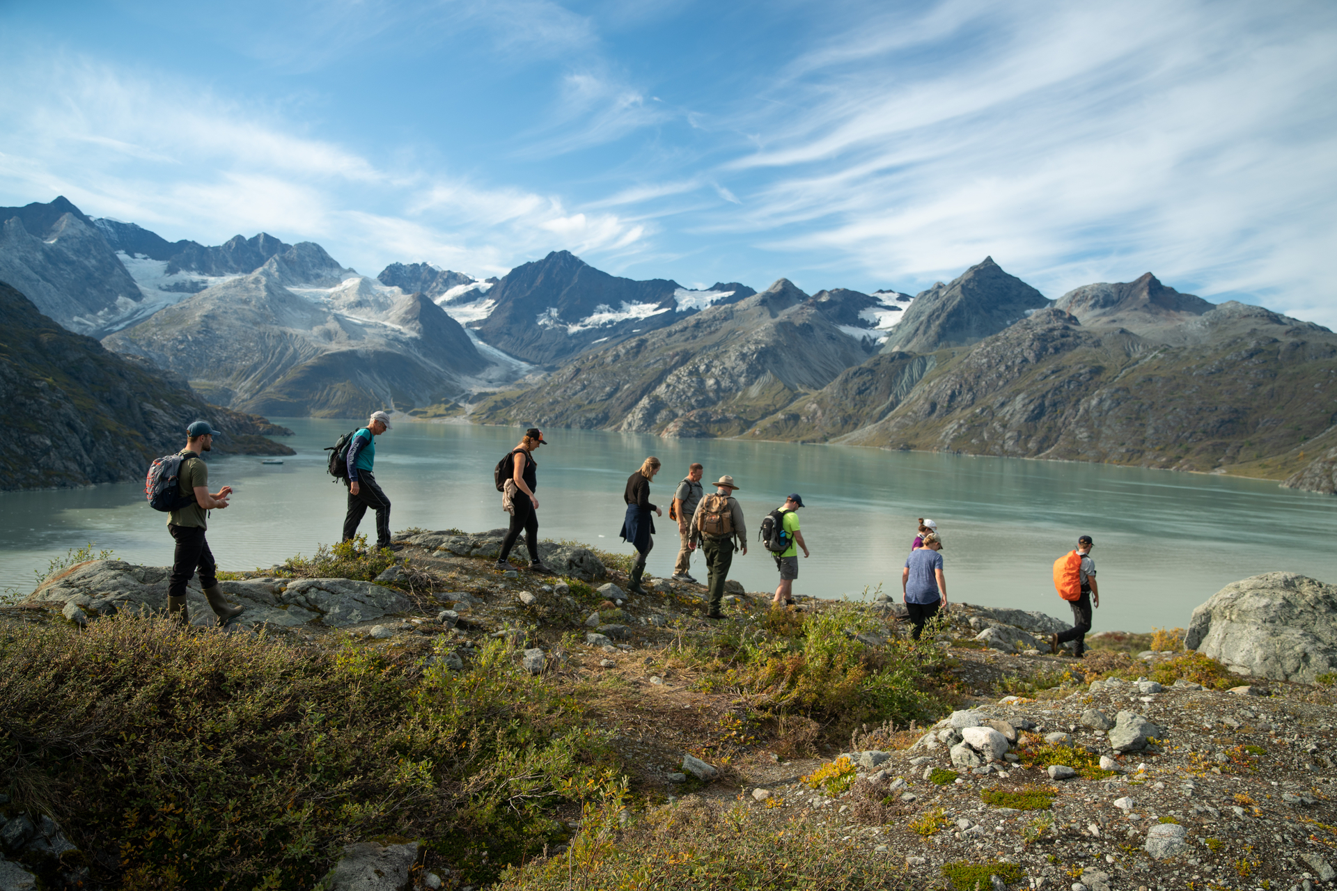 People hiking along a ridgeline in Alaska, mountains in the distance