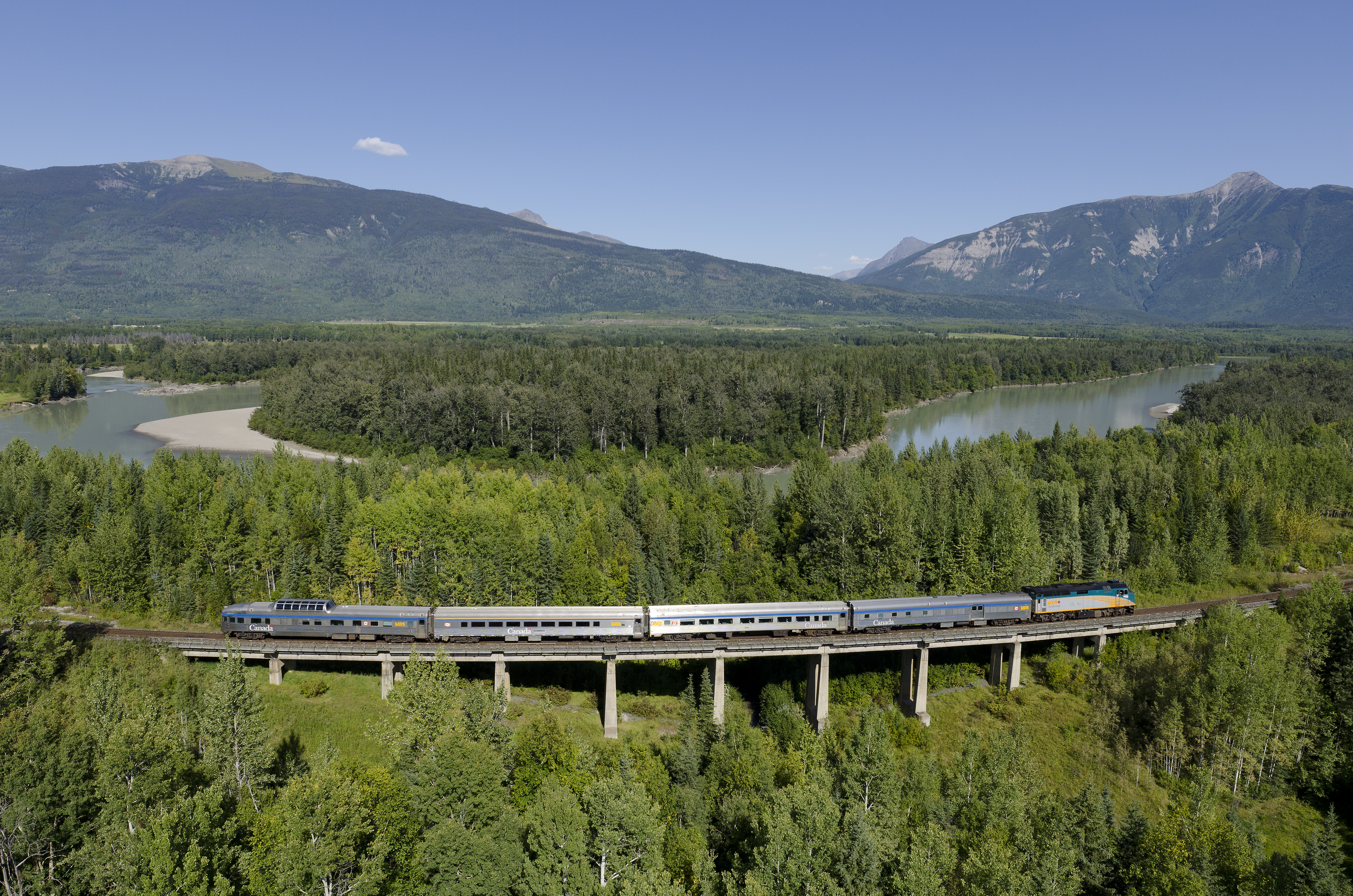 VIA Rail train with a view of lake and trees in the Canadian Rocky Mountains