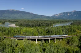 VIA Rail train with a view of lake and trees in the Canadian Rocky Mountains