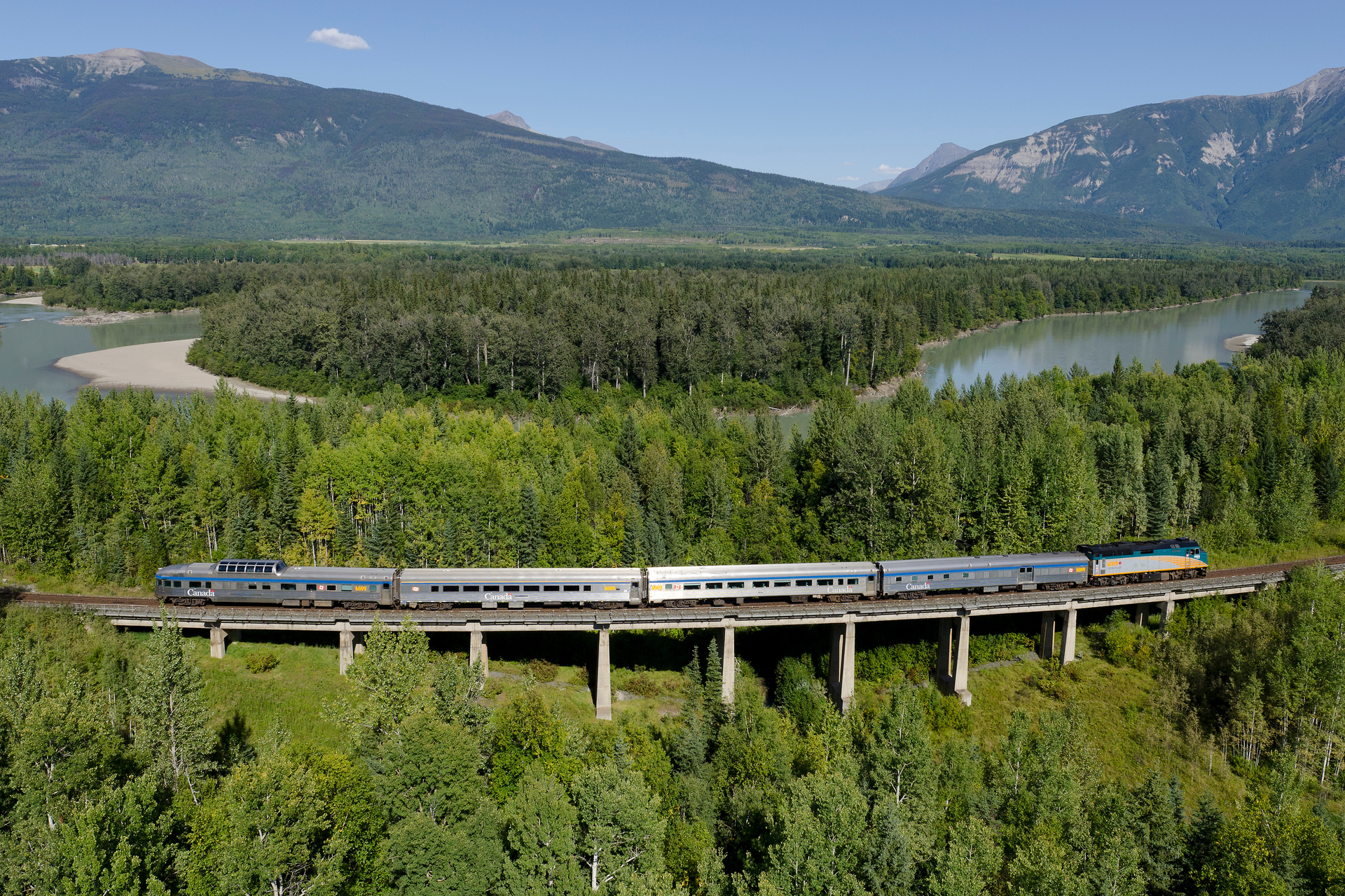 VIA Rail train with a view of lake and trees in the Canadian Rocky Mountains