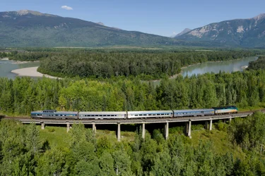 VIA Rail train with a view of lake and trees in the Canadian Rocky Mountains