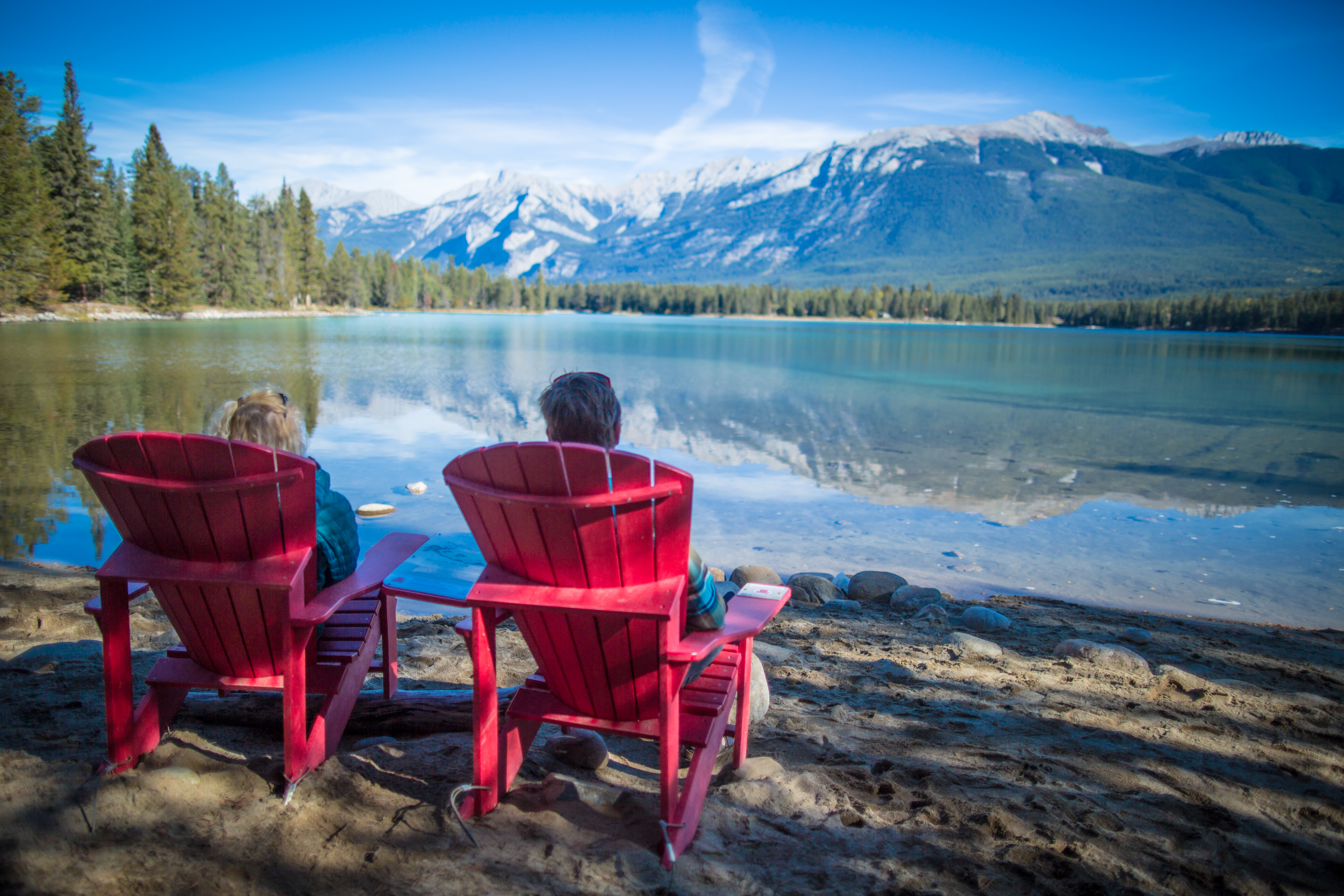 couple sitting in red adirondack chairs near Lake Edith