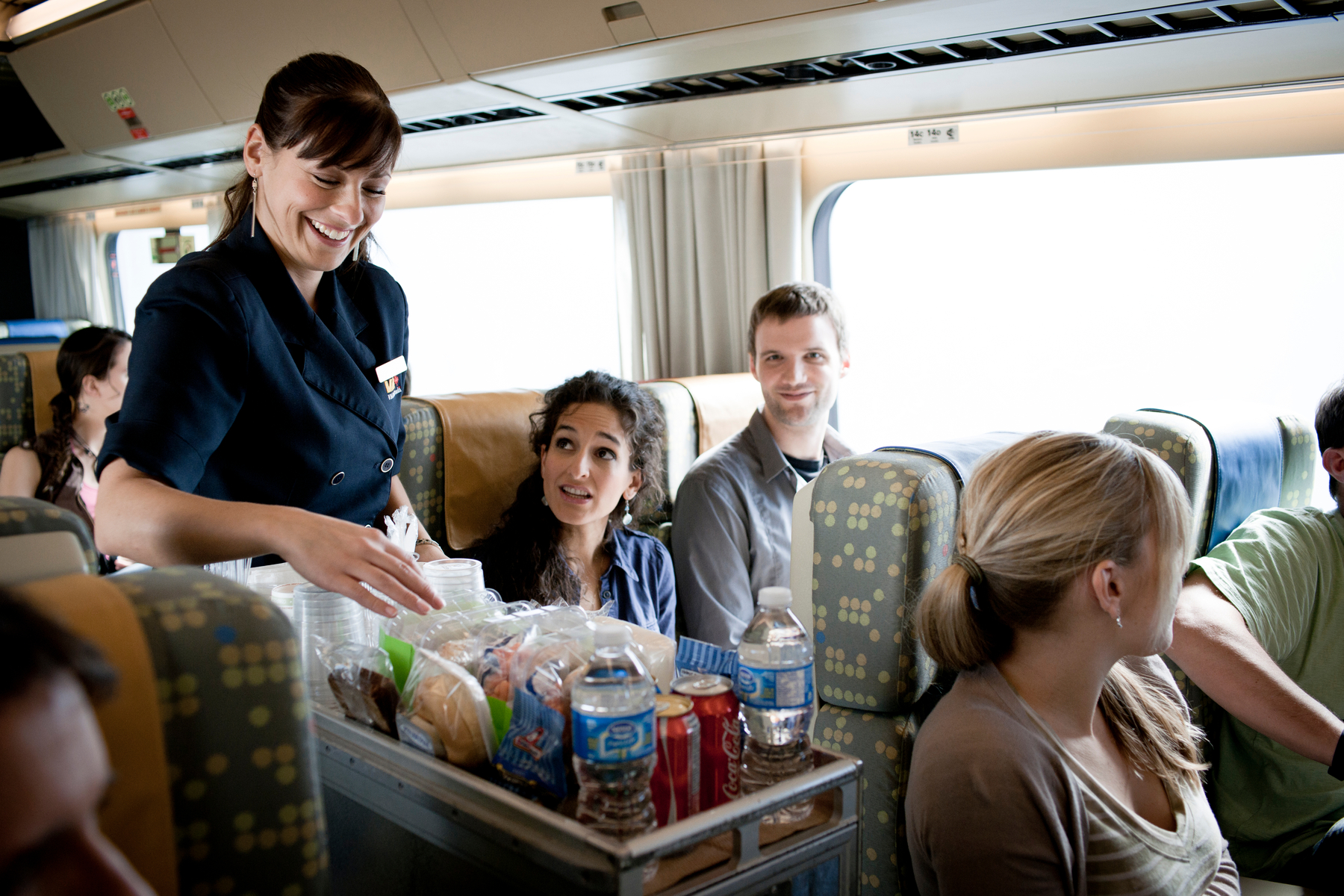 VIA Rail attendant serves couple seated in Economy train car on the way to the Canadian Rockies
