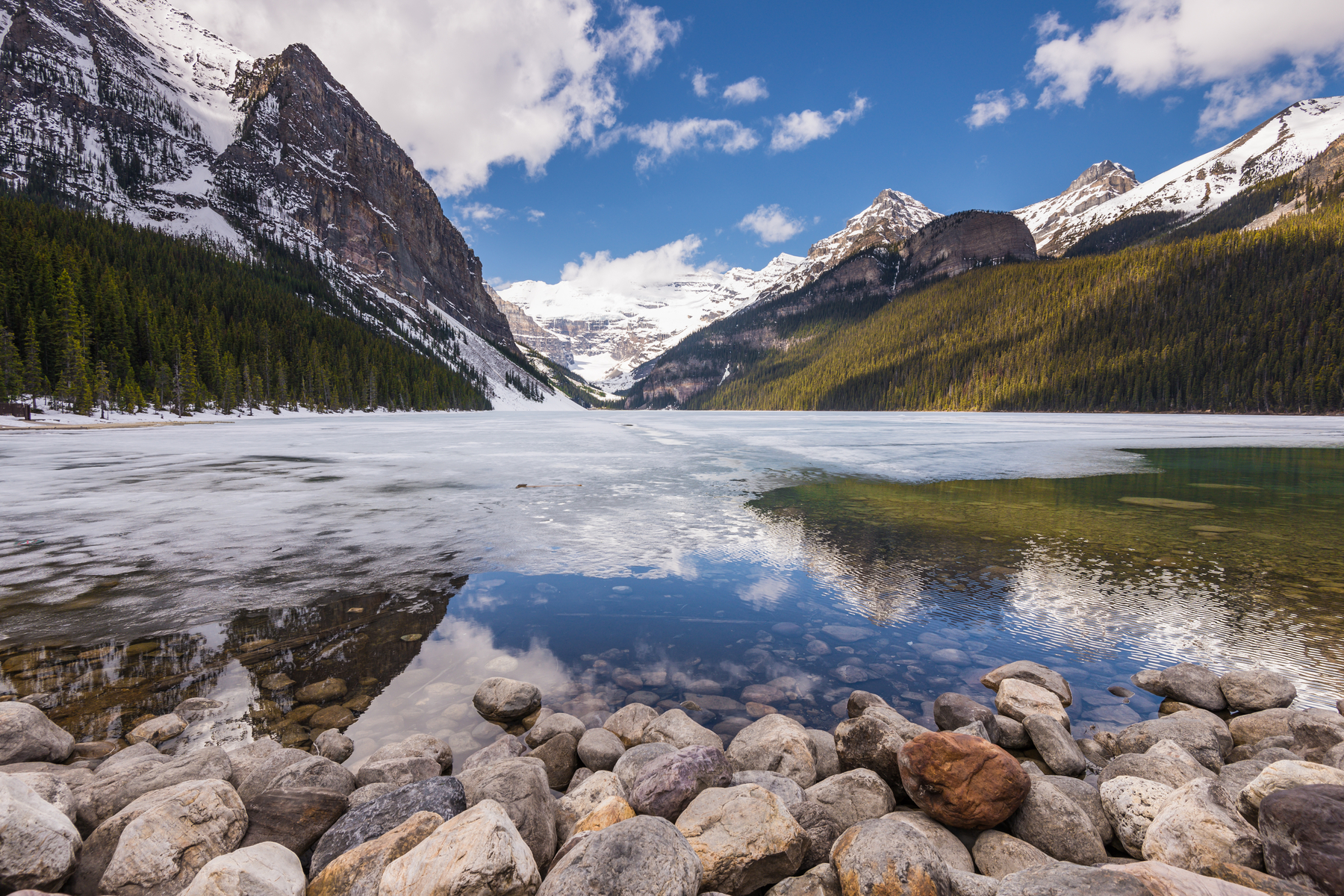 Snow-capped mountains around half-frozen Lake Louise in spring