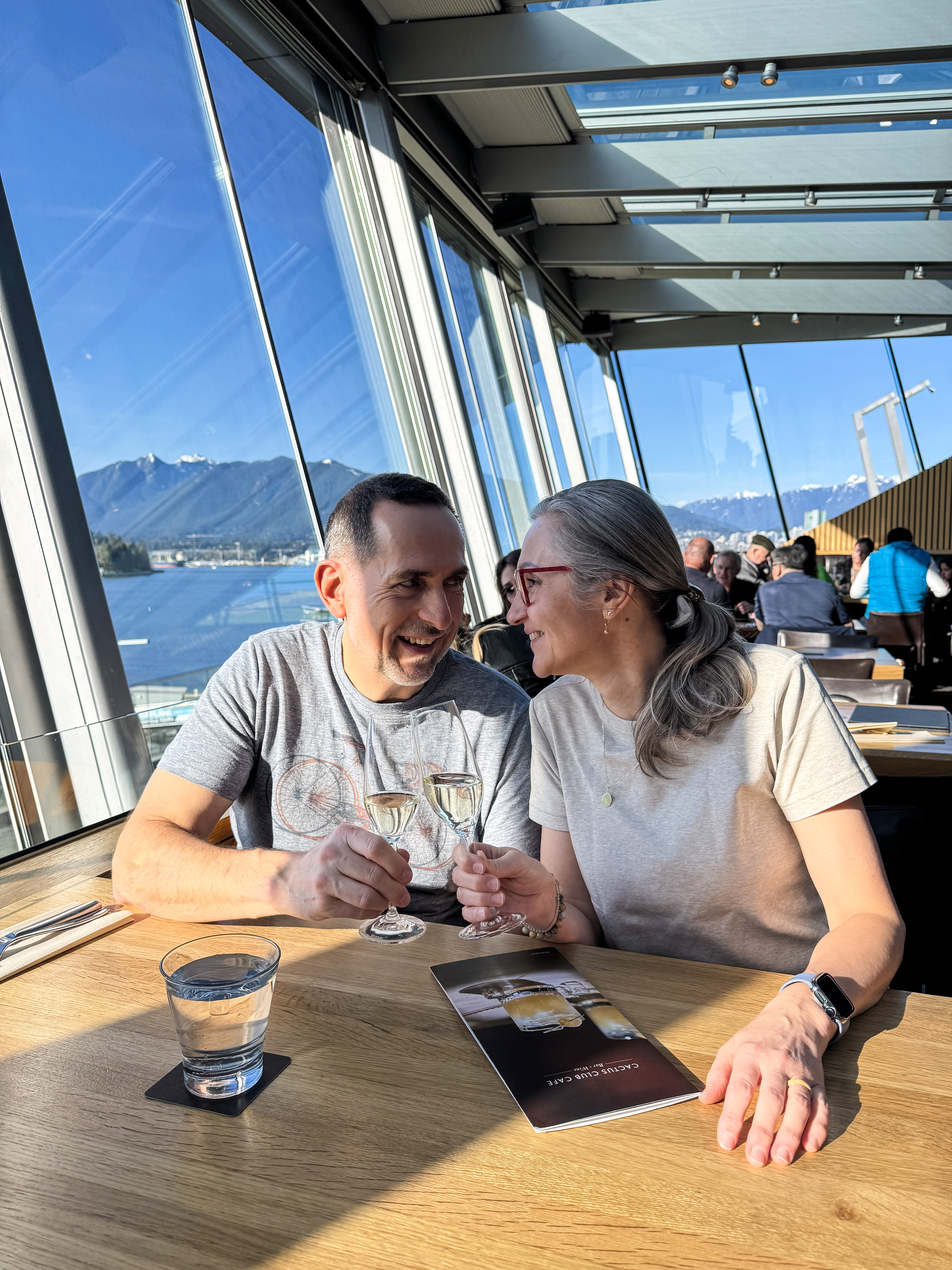Couple sharing a drink at a restaurant in downtown Vancouver, views of the waterfront out the window