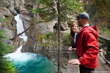 Couple standing on a bridge overlooking a waterfall in Johnston Canyon in the Canadian Rockies