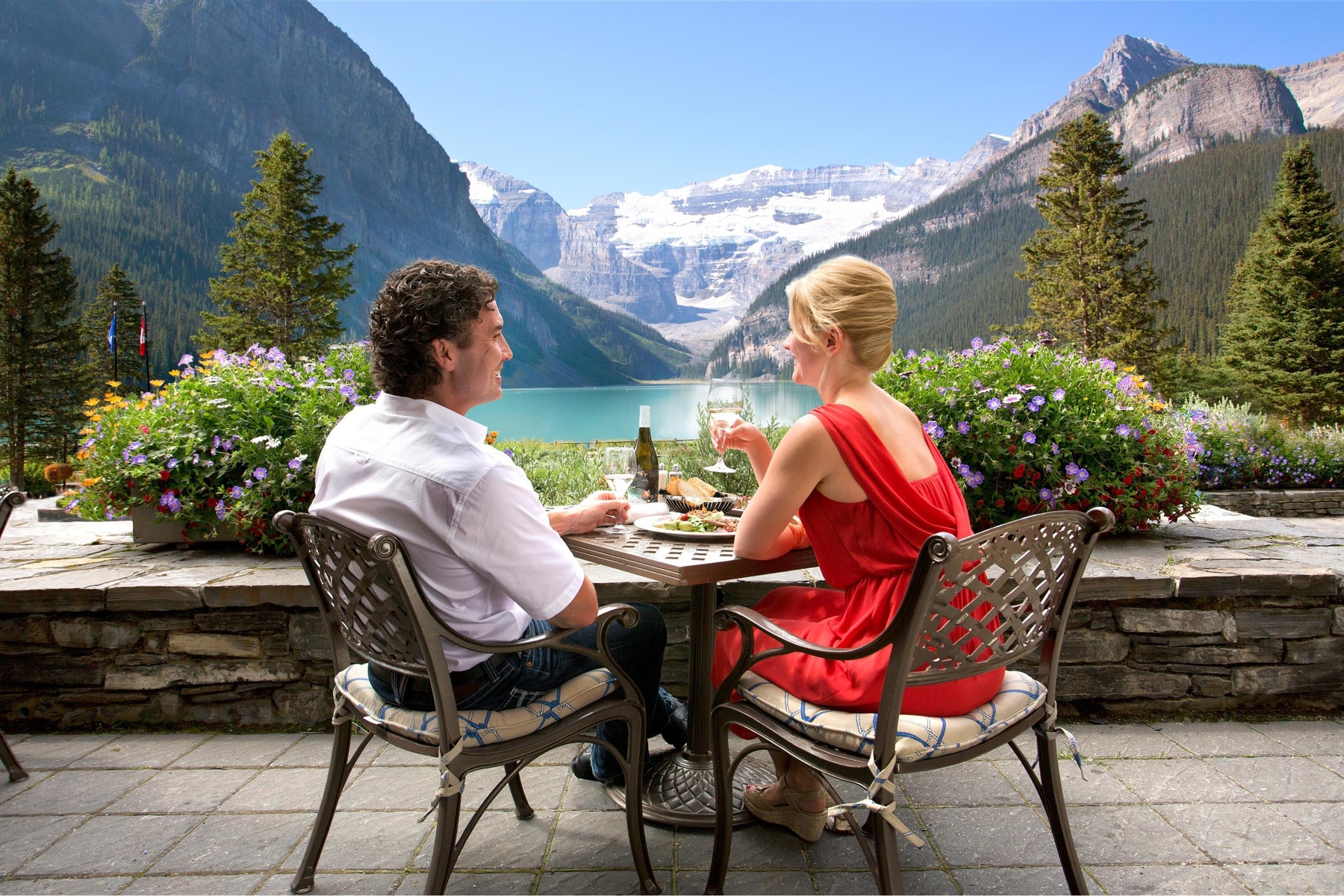 Couple sitting on a terrace with a drink overlooking Lake Louise