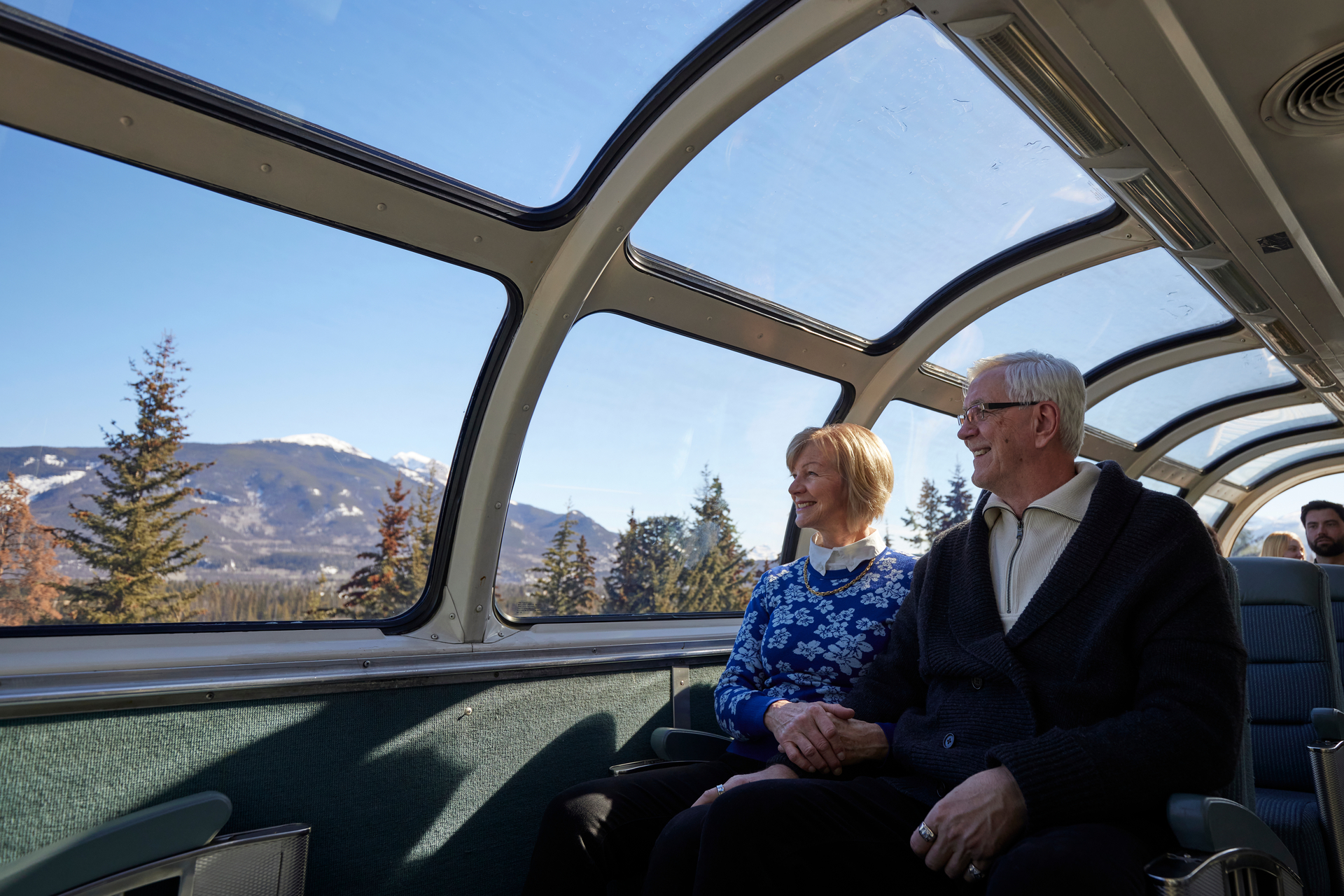 Couple enjoying view of rockies from the upper deck dome on a VIA Rail train