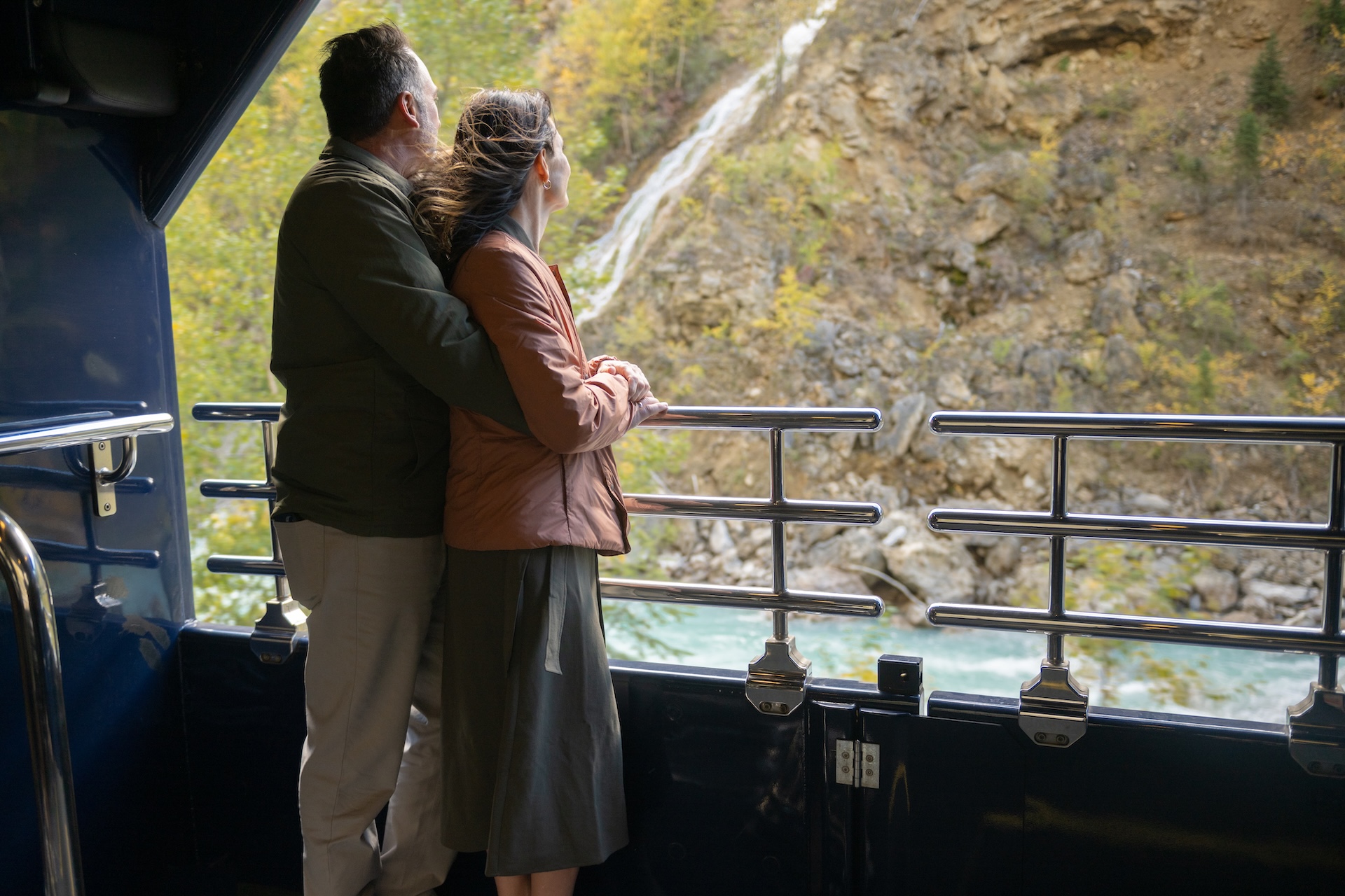 Guests looking at waterfall scenery from the outdoor viewing platform on the Rocky Mountaineer Train
