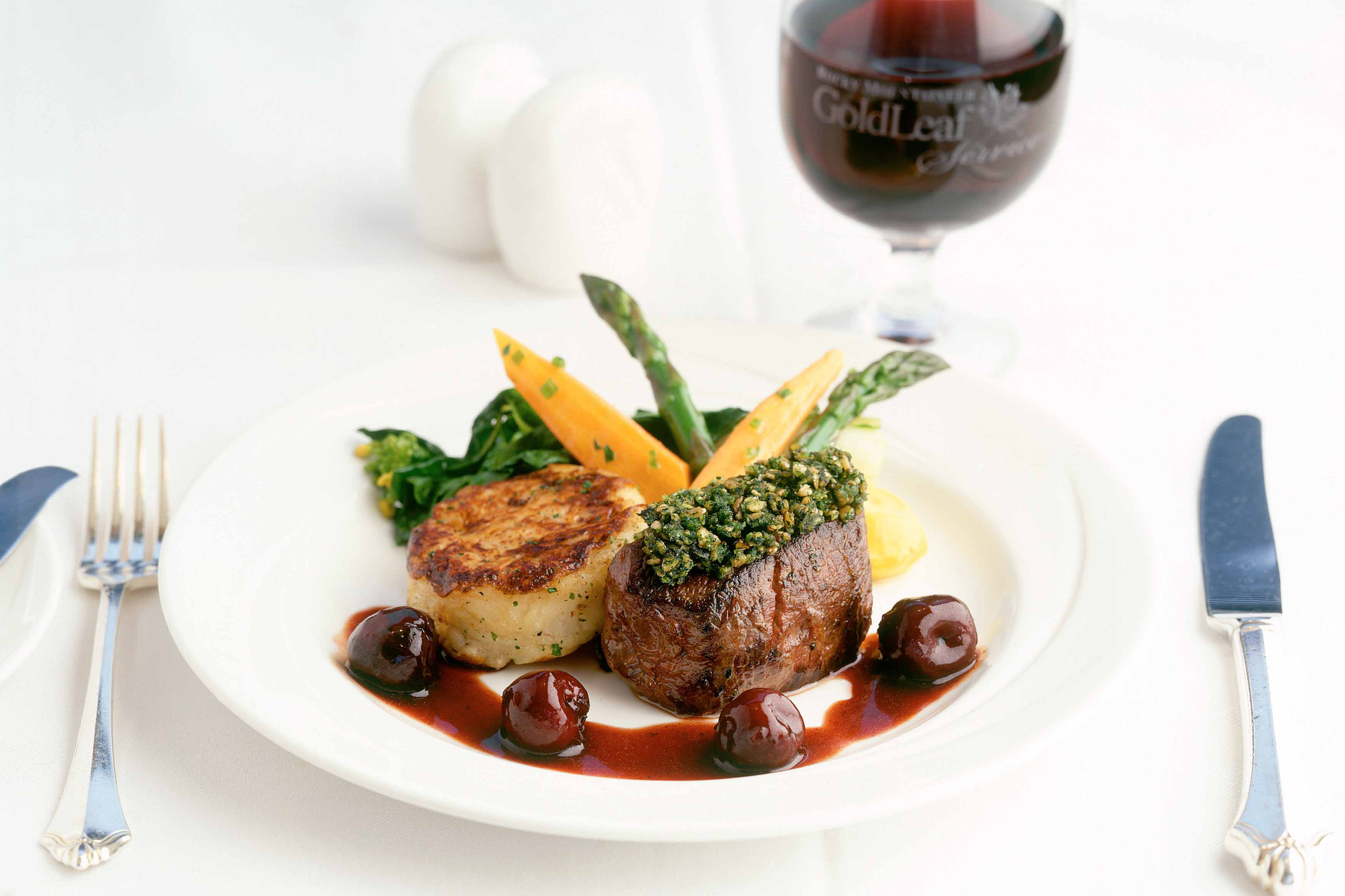 A meal of beef and potato with a glass of red wine in the background.