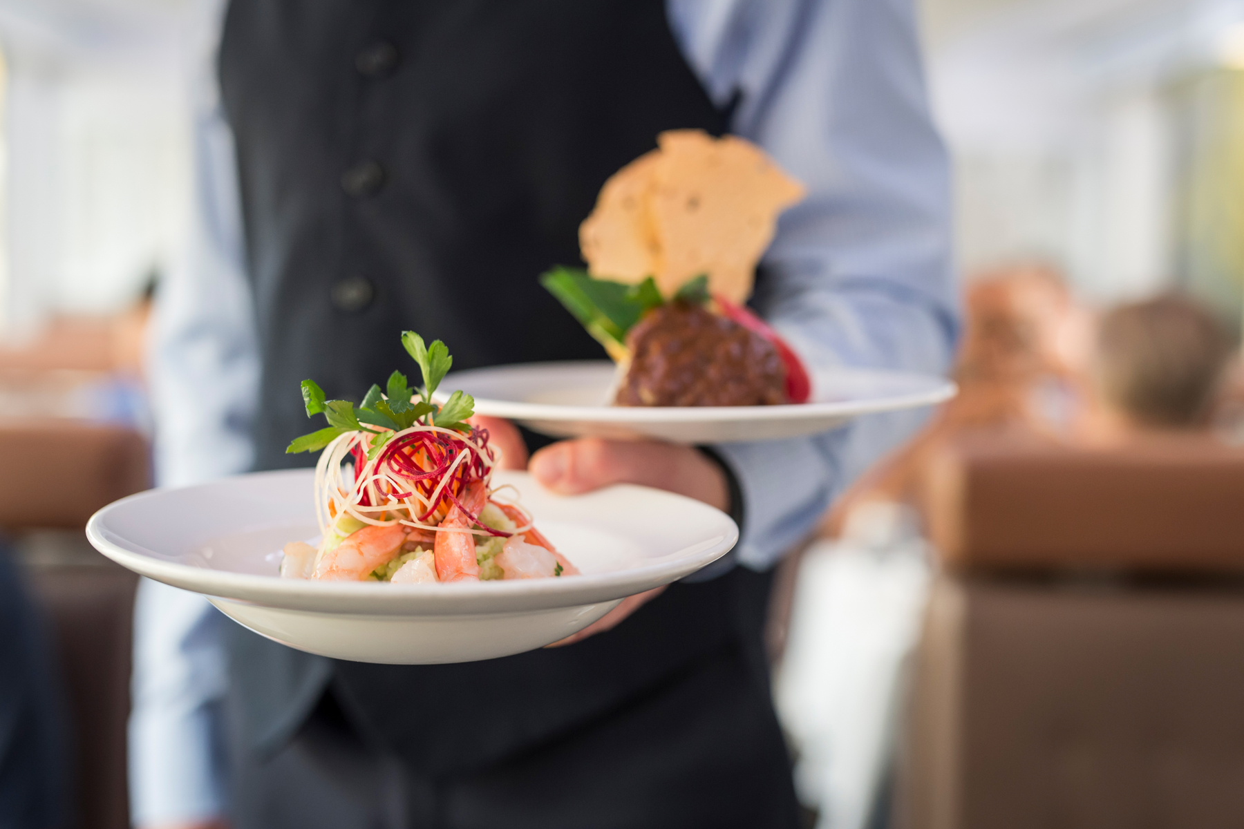 A dish of pacific prawns and beef short ribs held by a server