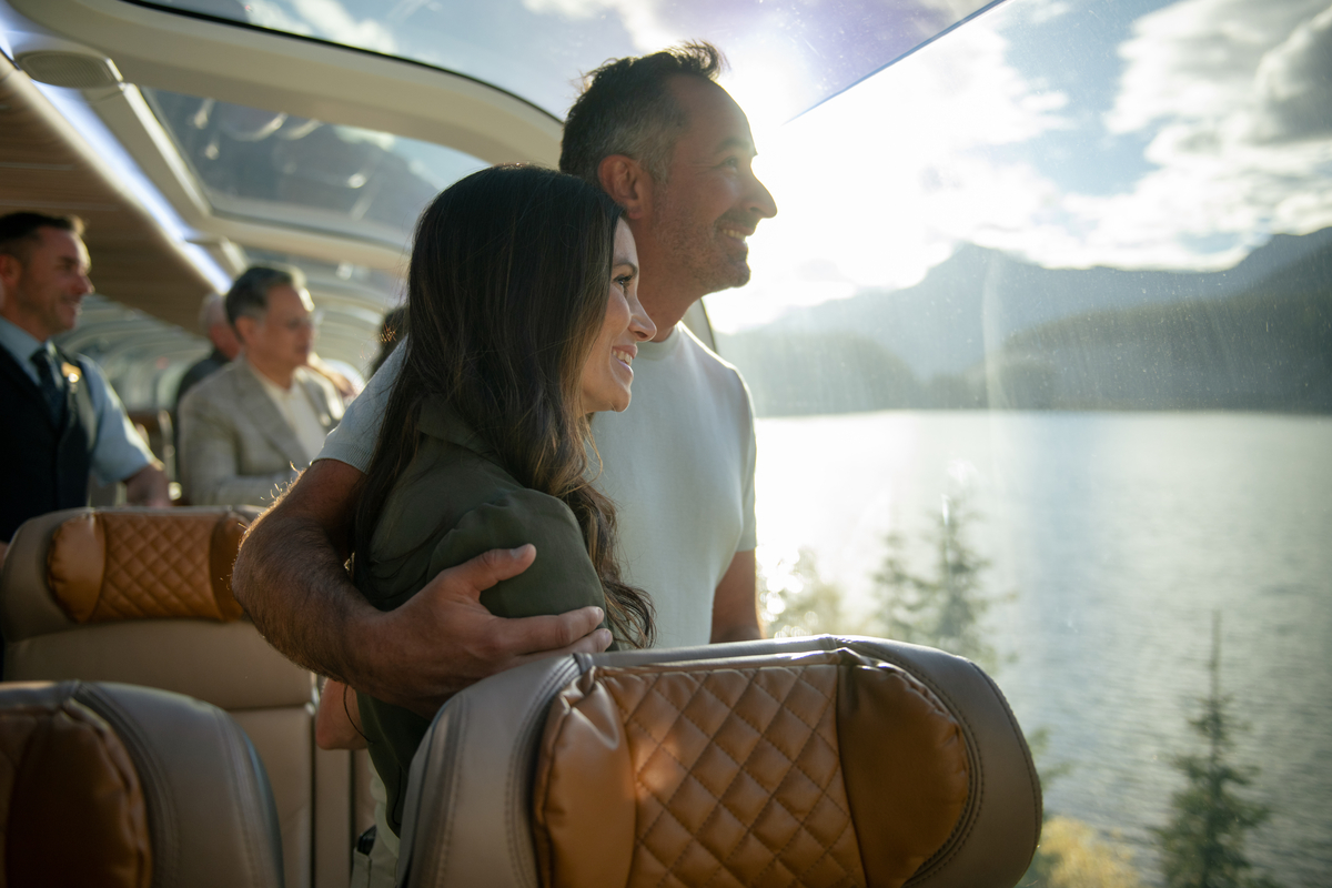 Guests looking at lake scenery from their seats in GoldLeaf onboard the Rocky Mountaineer Train