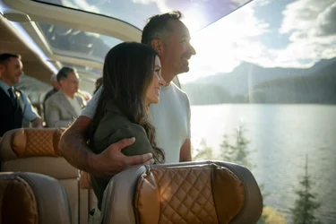 Guests looking at lake scenery from their seats in GoldLeaf onboard the Rocky Mountaineer Train