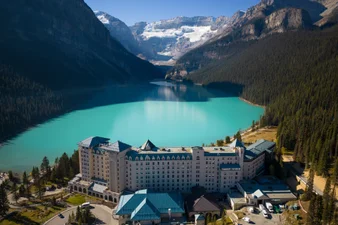 Aerial shot of Fairmont Chateau Lake Louise in front of turquoise lake and glacier