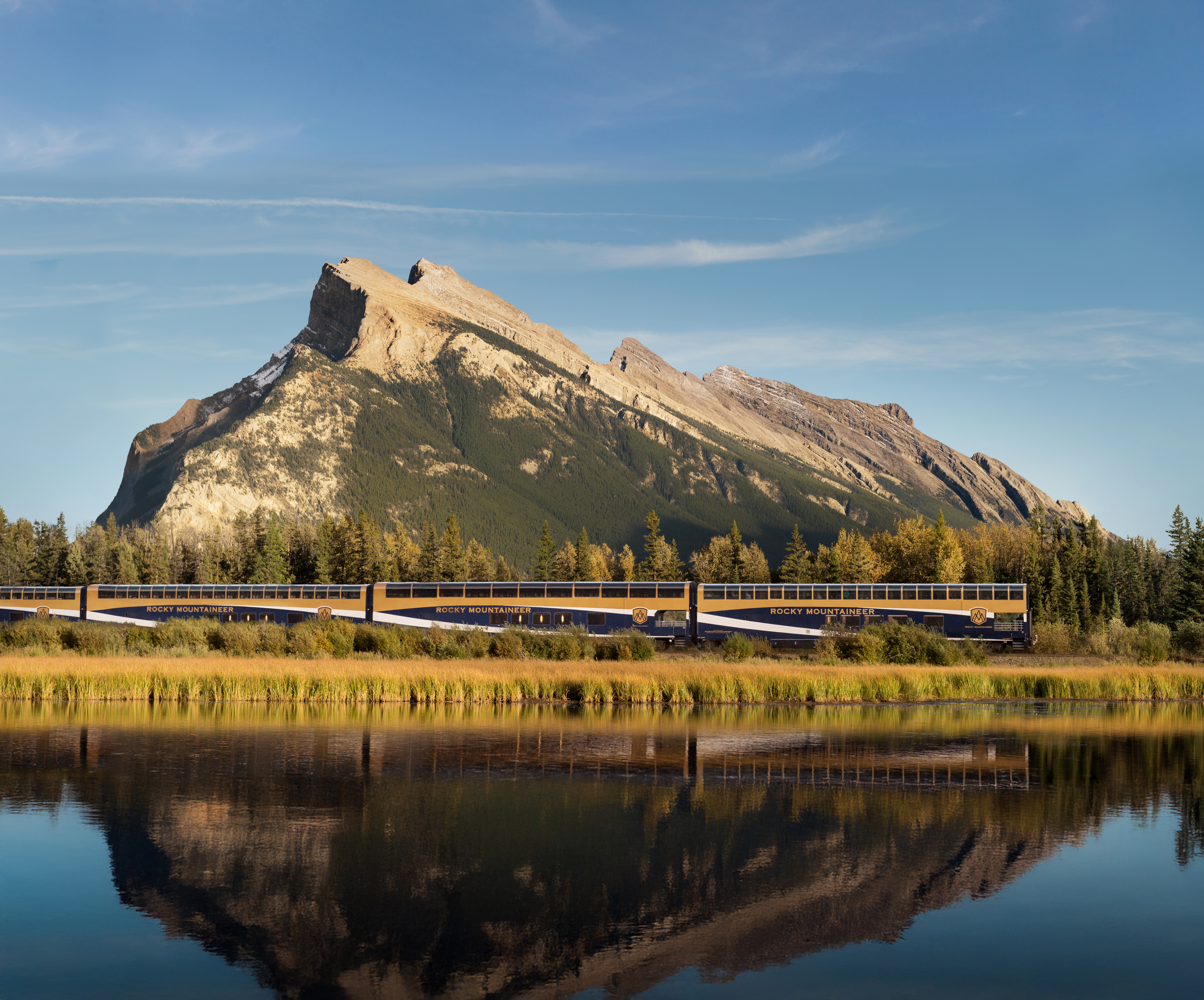 Rocky Mountaineer train passing a jagged mountain near Banff