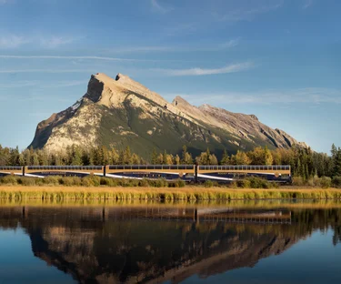 Rocky Mountaineer train passing a jagged mountain near Banff