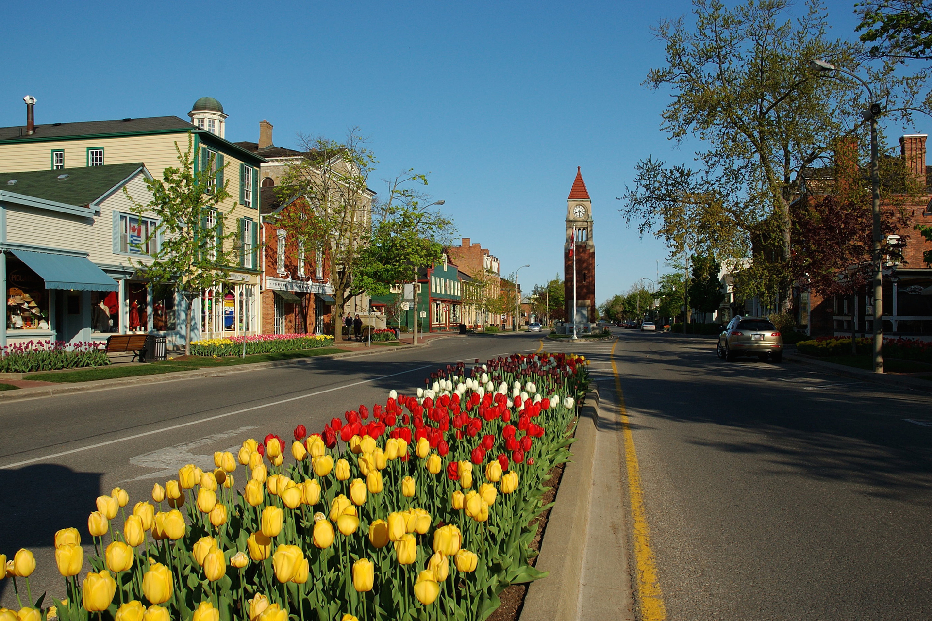 A view looking west along Queen Street, Niagara on the Lake, Ontario, Canada showing the profusion of spring flowers, with the Clock Tower.
