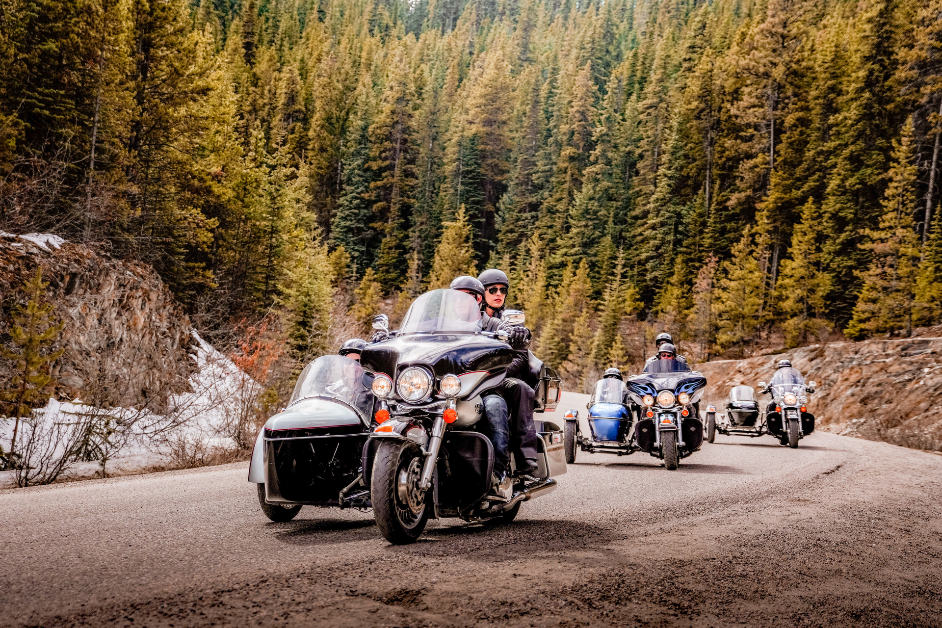 A group of motorcyclists with side cars riding through the Rockies