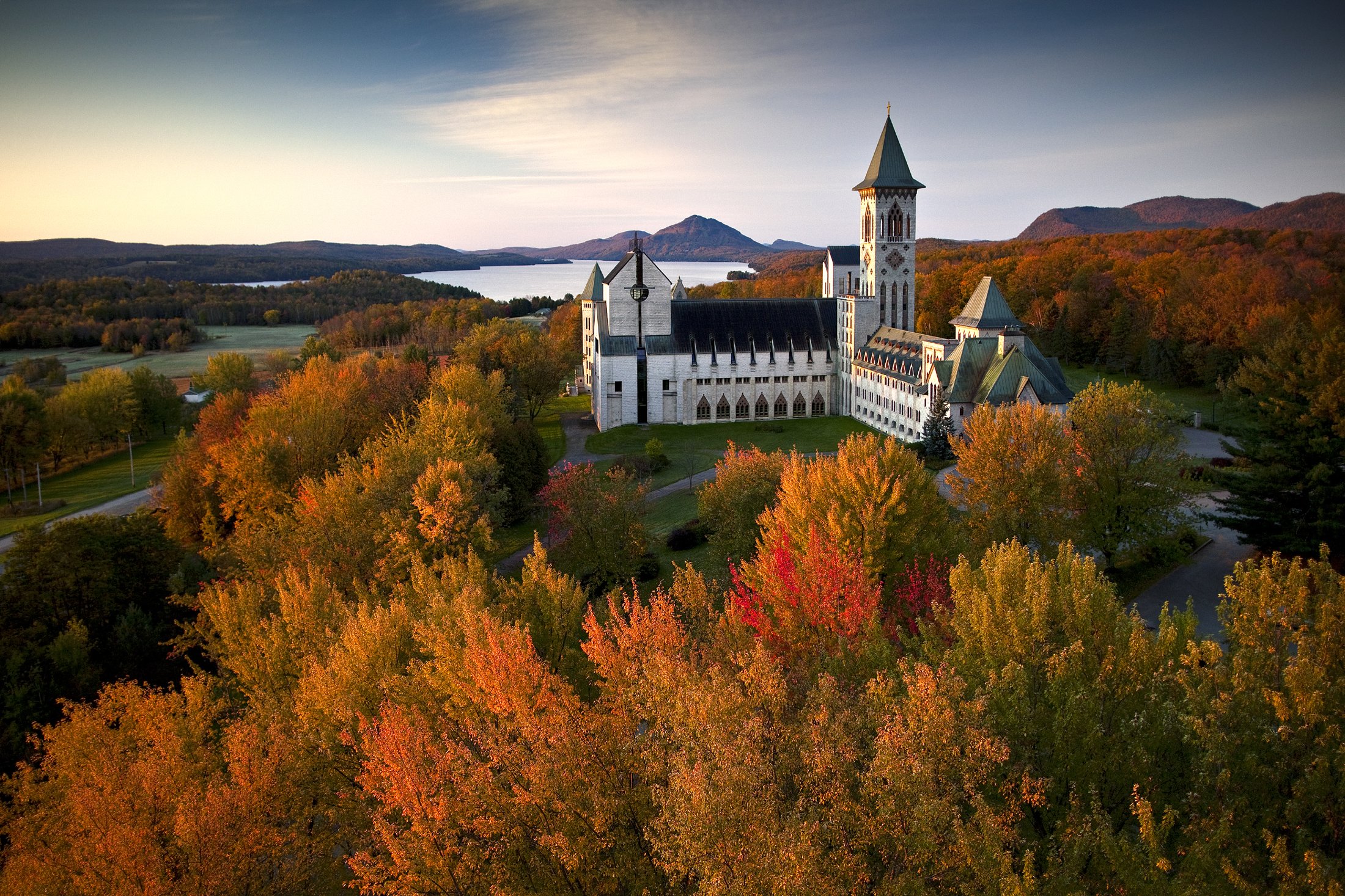 Saint Bennedict Abbey on a hill surrounded by fall foliage with lake in the distance