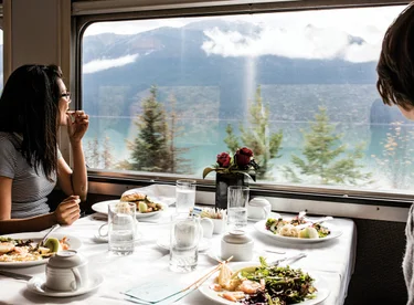 two people looking out a window in a train while eating