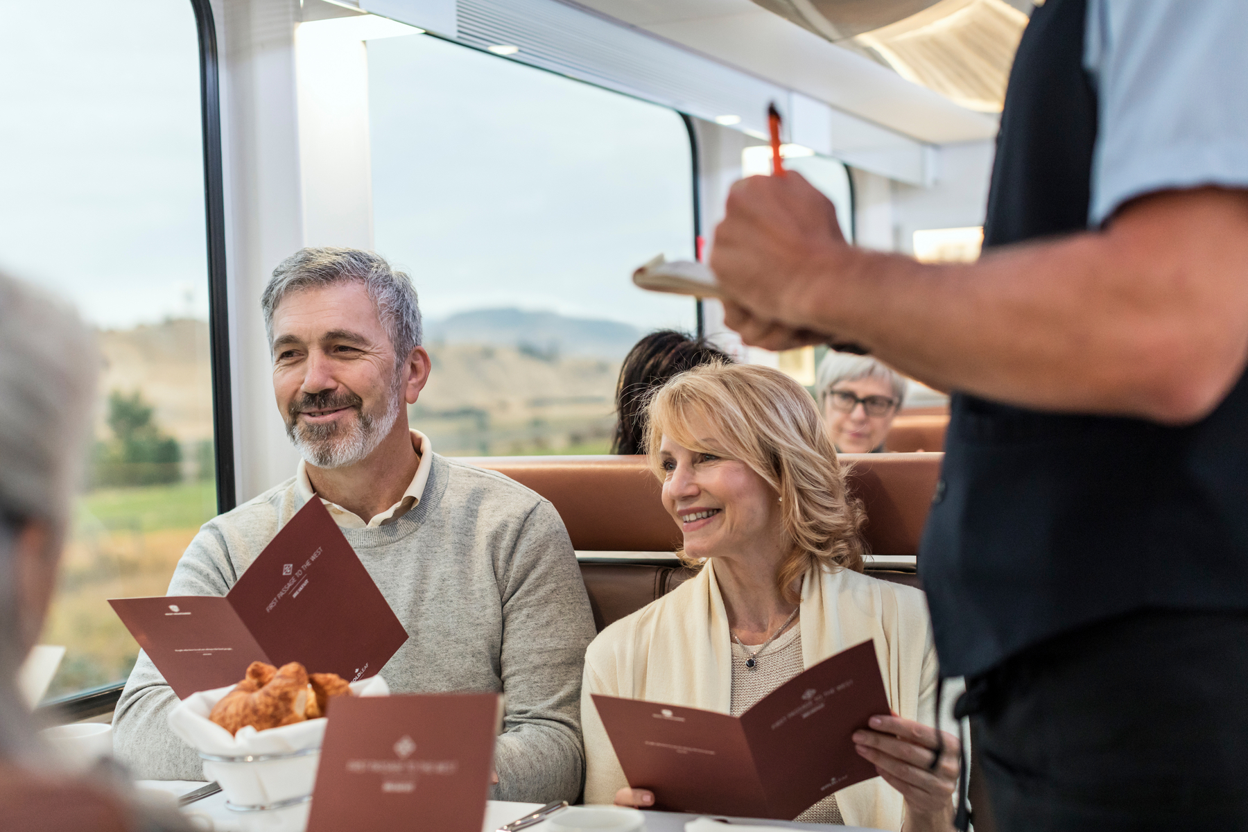 Onboard host taking meal order from guests in the GoldLeaf dining room