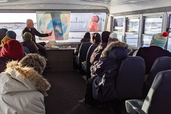 Guide points to a map as he talks about Churchill to guests in a tundra buggy