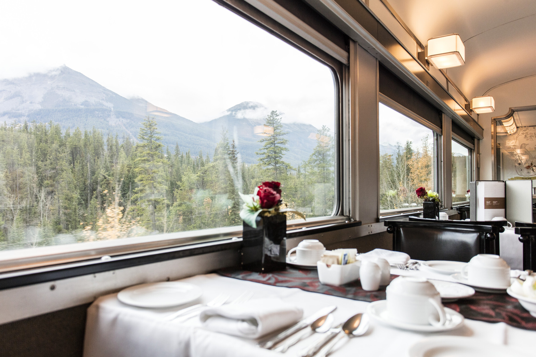 Table set up in the dining car of VIA Rail Canadian Train, with views of the mountains out the window
