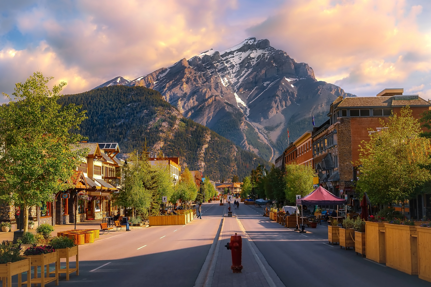 A colourful sunrise sky over a road leading through the town of Banff in the summertime.