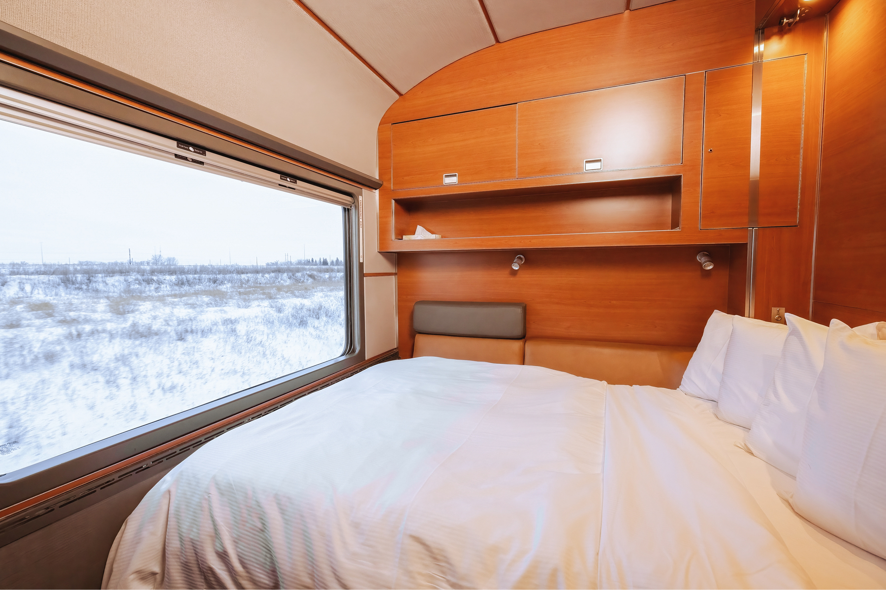 Made Murphy bed facing extra-large window of Prestige Sleeper cabin in VIA Rail's train, The Canadian, during winter