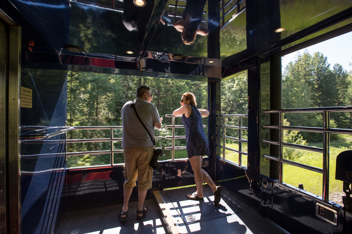 Couple standing on the Rocky Mountaineer GoldLeaf service outdoor viewing platform