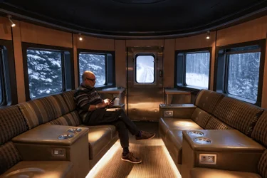Mature man relaxes in Prestige Park car Bullet Lounge seat onboard VIA Rail's train, The Canadian, during winter